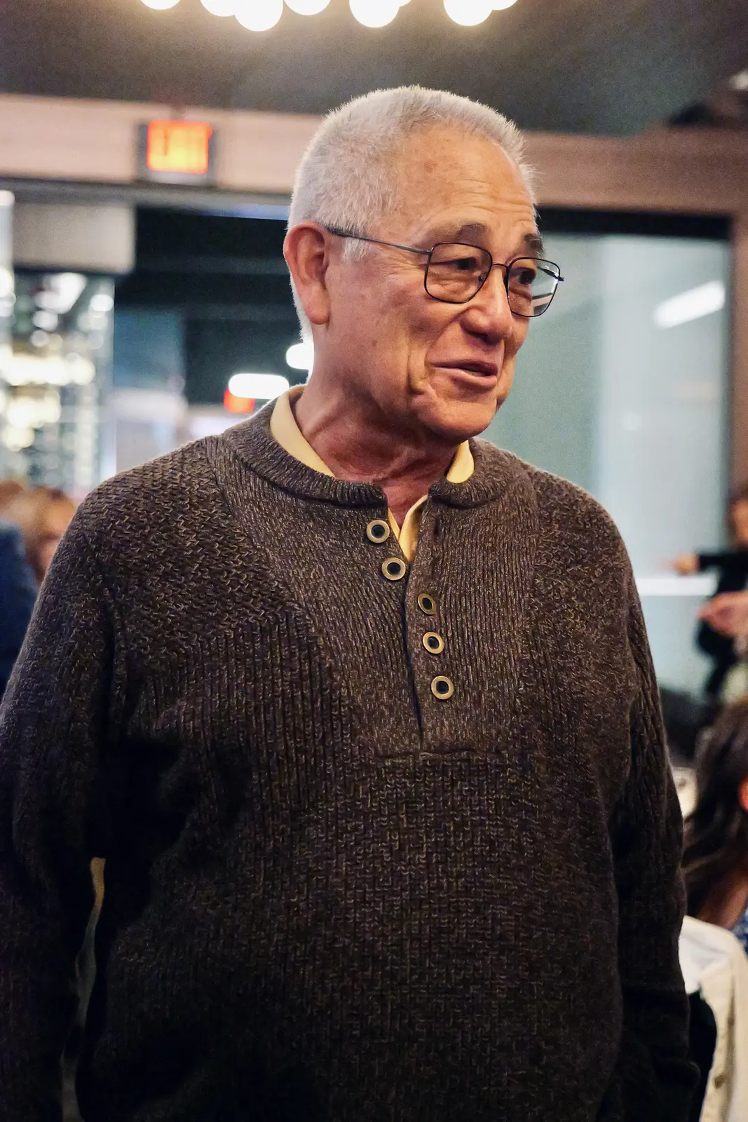 Guest in a brown knit sweater, smiling mid-conversation