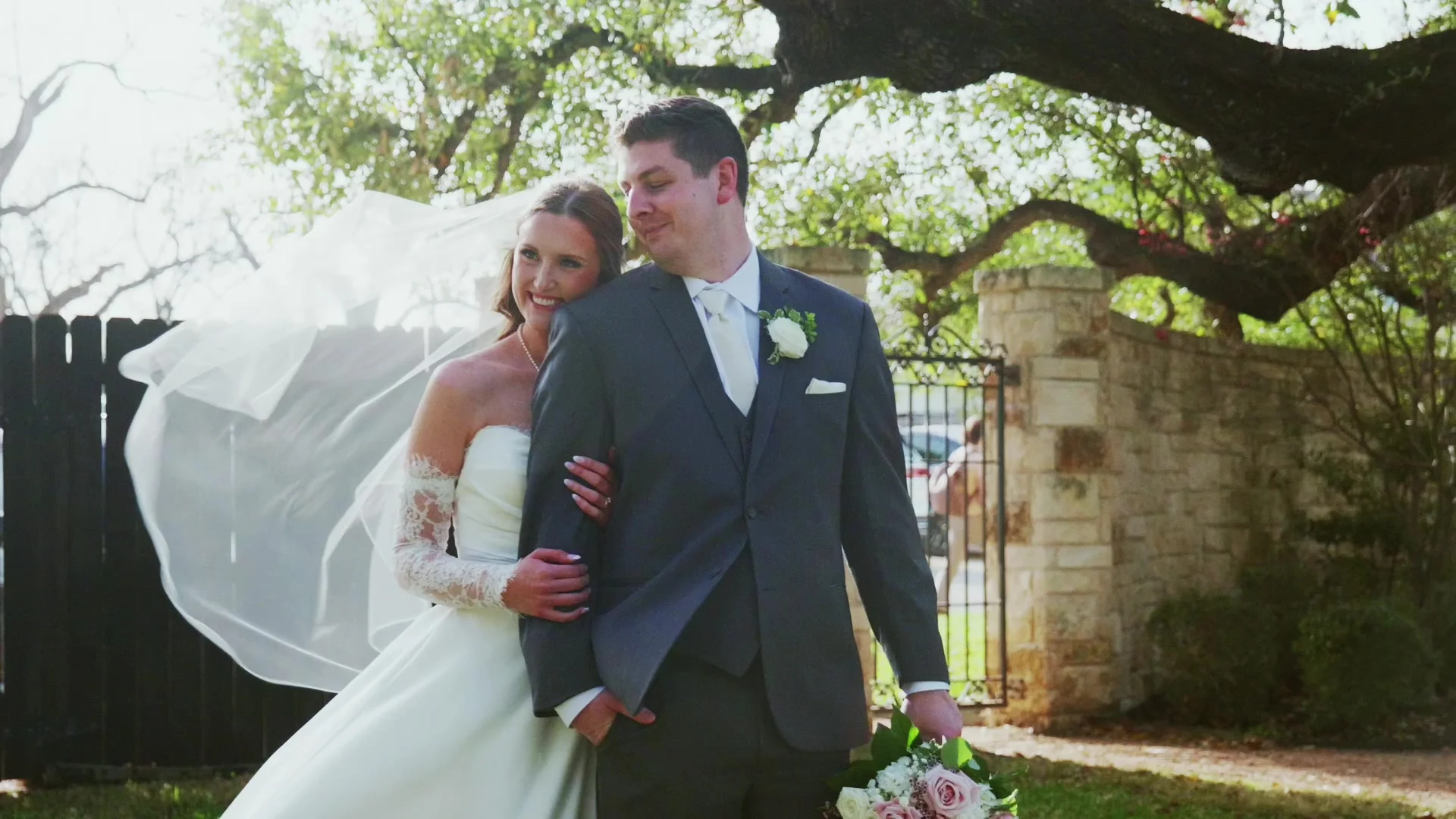 Bride and groom on their wedding day, her veil lifting in the wind